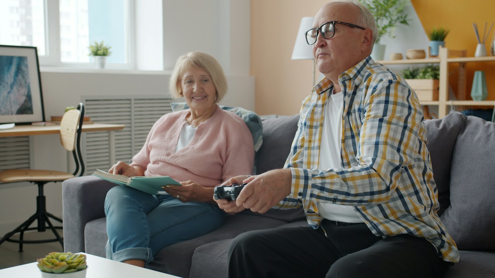 An older couple relax on their couch in front of the TV.